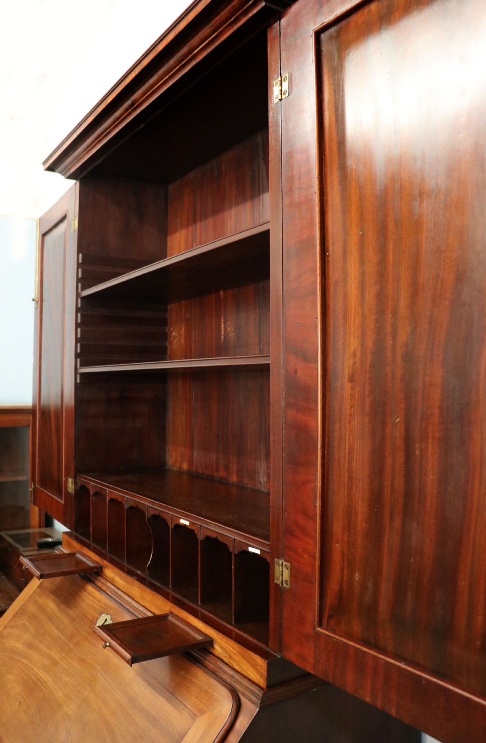 A George III mahogany bureau bookcase featuring a panelled upper cabinet above a fall-front writing surface and graduated drawers with brass hardware. View XXIX