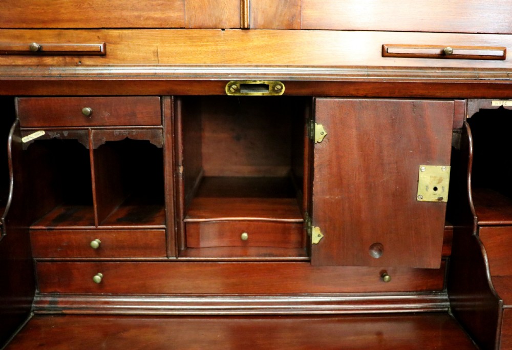A George III mahogany bureau bookcase featuring a panelled upper cabinet above a fall-front writing surface and graduated drawers with brass hardware. View XXX