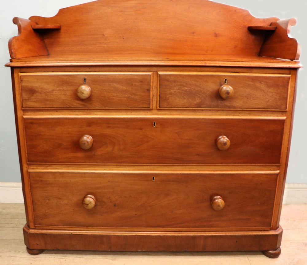 A mid-nineteenth century mahogany chest of drawers featuring two short drawers over two long drawers, turned wooden handles, and a shaped galleried backboard. View II