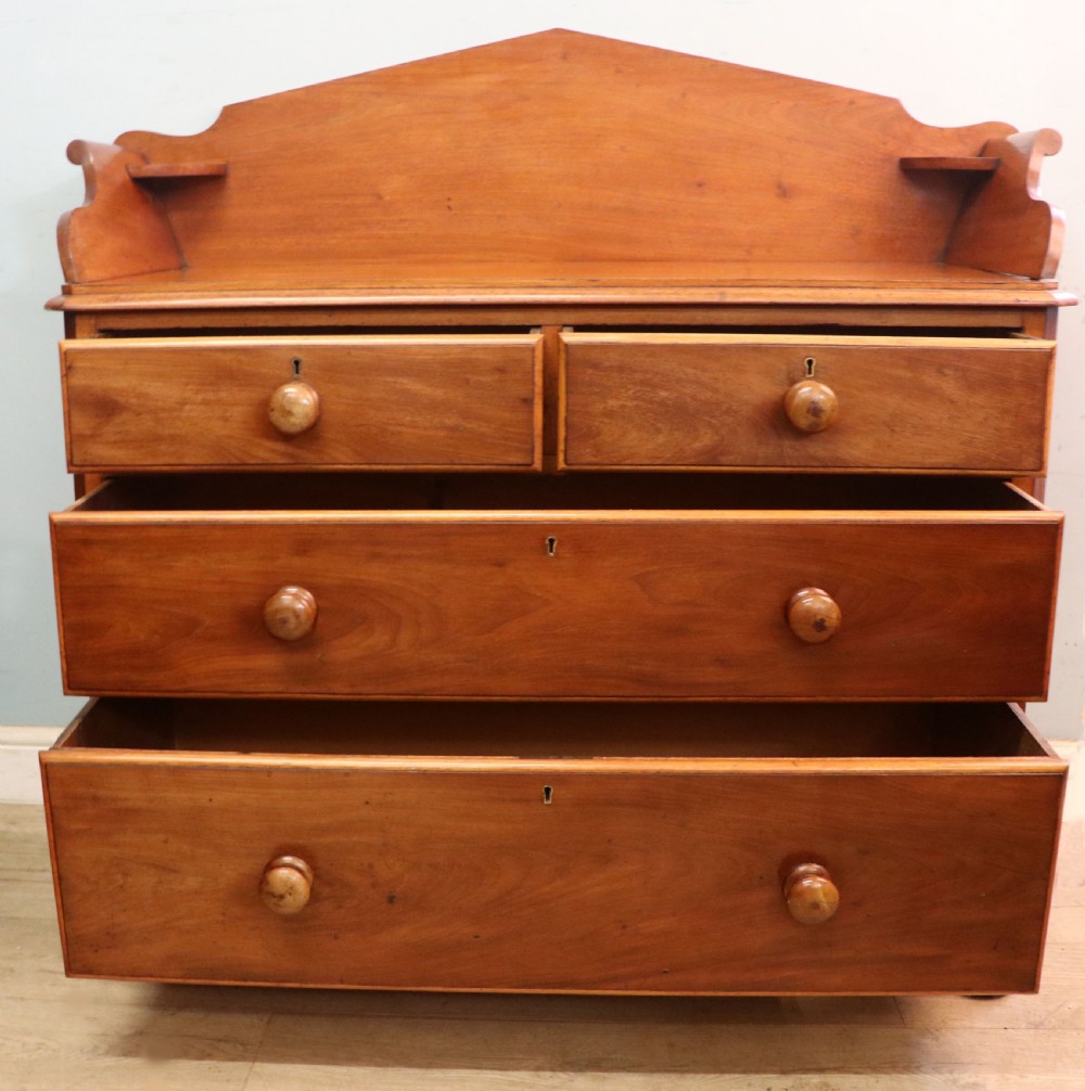 A mid-nineteenth century mahogany chest of drawers featuring two short drawers over two long drawers, turned wooden handles, and a shaped galleried backboard. View III