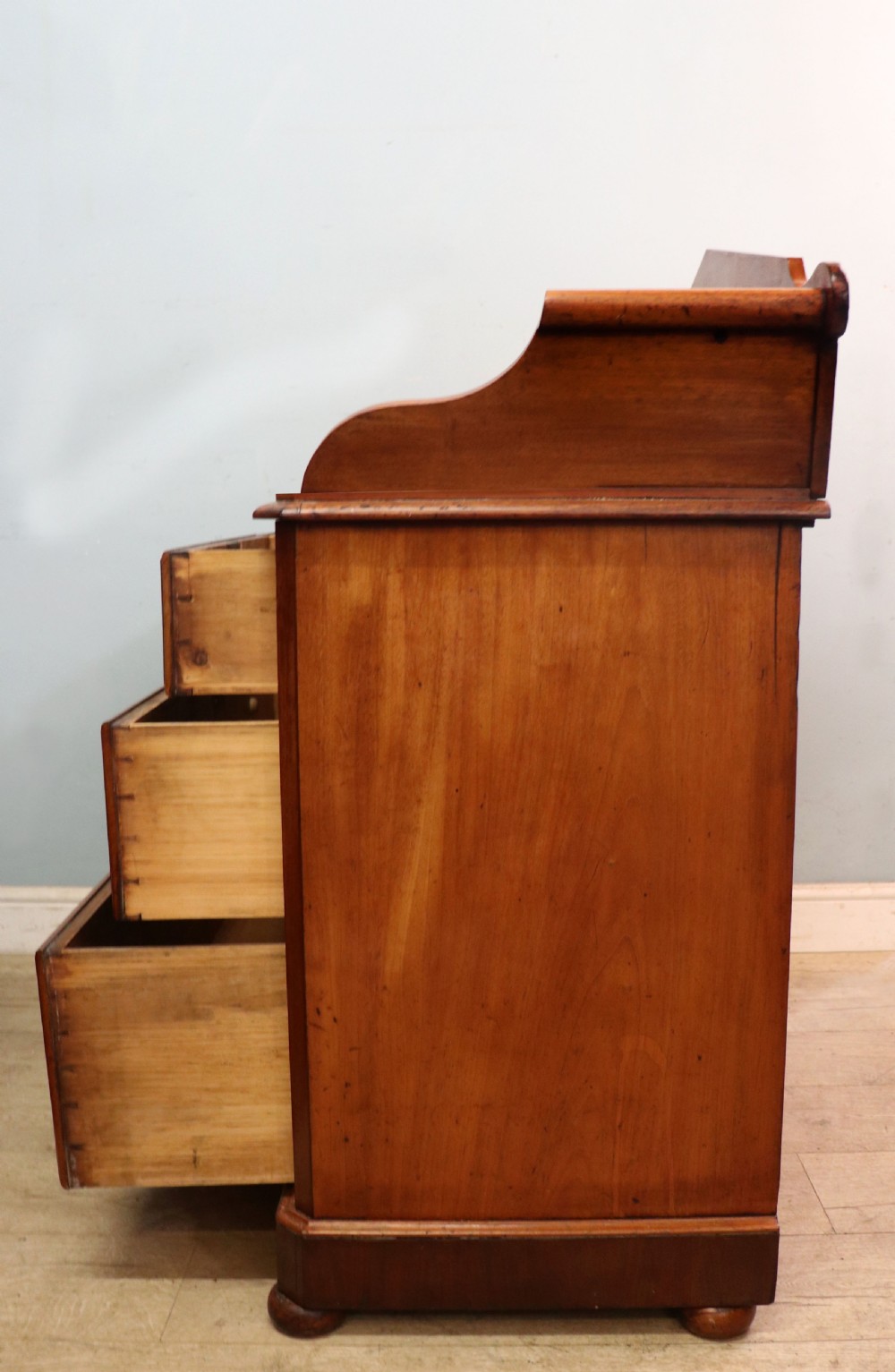A mid-nineteenth century mahogany chest of drawers featuring two short drawers over two long drawers, turned wooden handles, and a shaped galleried backboard. View V