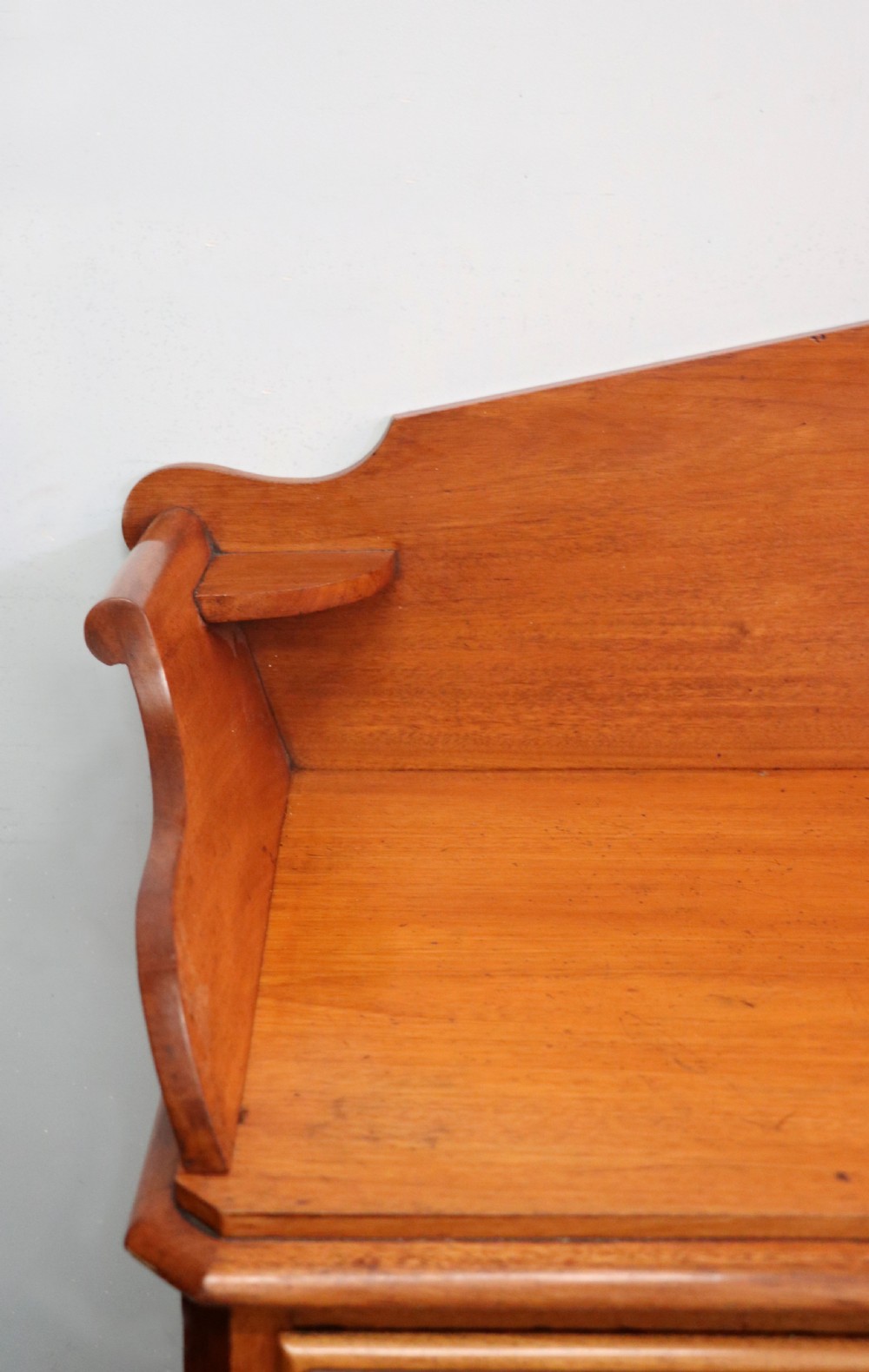 A mid-nineteenth century mahogany chest of drawers featuring two short drawers over two long drawers, turned wooden handles, and a shaped galleried backboard. View VIII