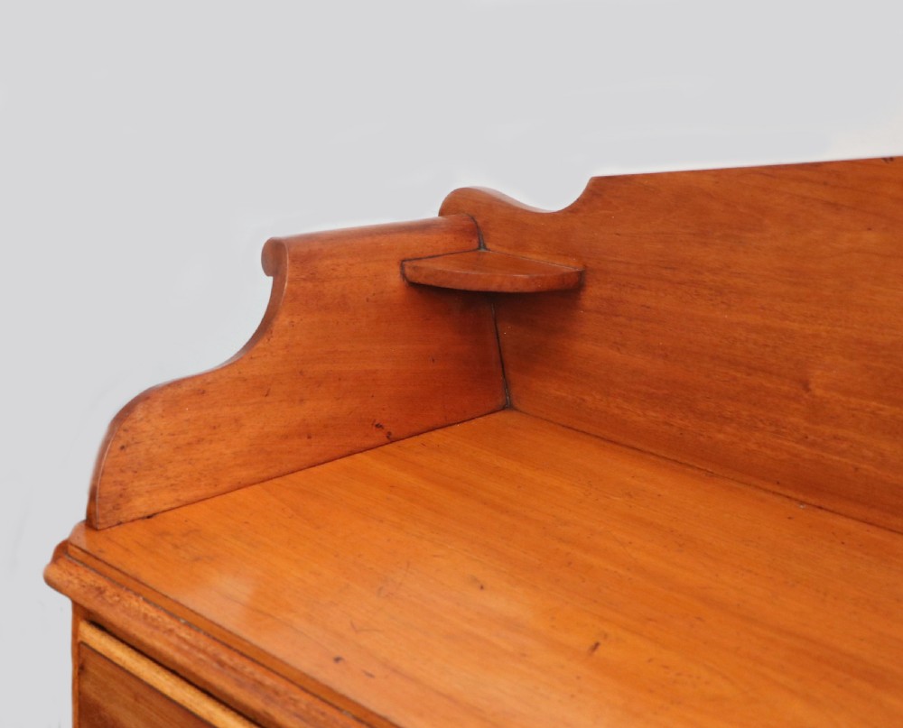 A mid-nineteenth century mahogany chest of drawers featuring two short drawers over two long drawers, turned wooden handles, and a shaped galleried backboard. View IX