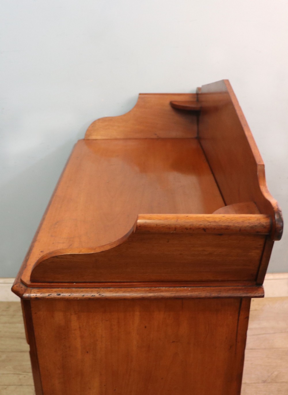 A mid-nineteenth century mahogany chest of drawers featuring two short drawers over two long drawers, turned wooden handles, and a shaped galleried backboard. View XIII