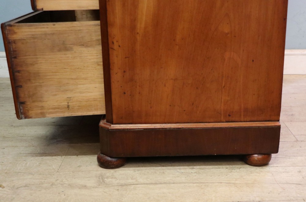 A mid-nineteenth century mahogany chest of drawers featuring two short drawers over two long drawers, turned wooden handles, and a shaped galleried backboard. View XIX