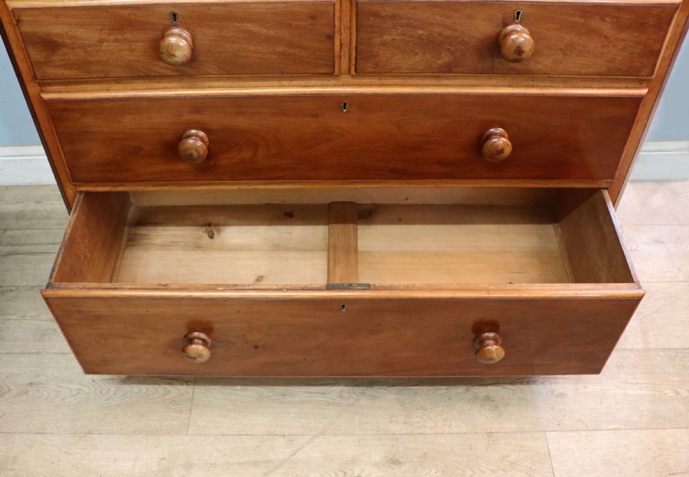 A mid-nineteenth century mahogany chest of drawers featuring two short drawers over two long drawers, turned wooden handles, and a shaped galleried backboard. View XX