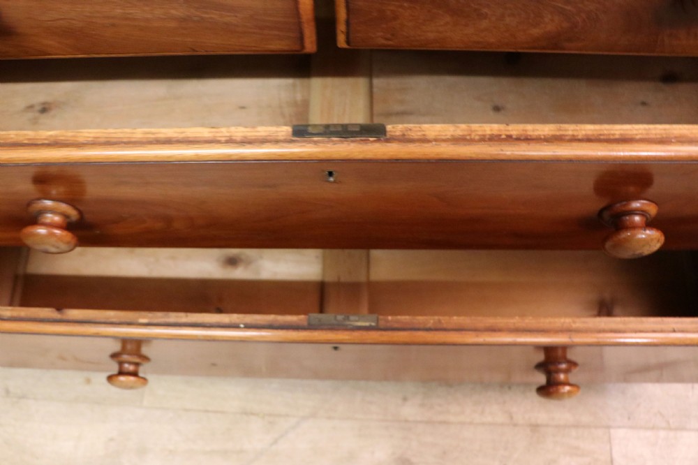 A mid-nineteenth century mahogany chest of drawers featuring two short drawers over two long drawers, turned wooden handles, and a shaped galleried backboard. View XXI