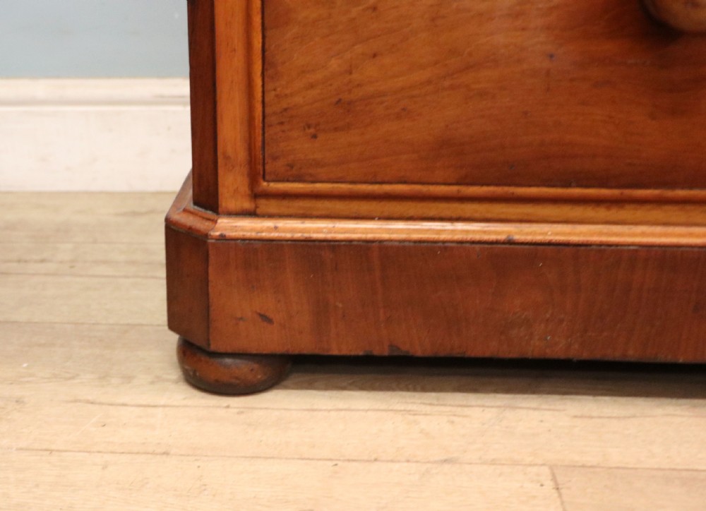 A mid-nineteenth century mahogany chest of drawers featuring two short drawers over two long drawers, turned wooden handles, and a shaped galleried backboard. View XXIII