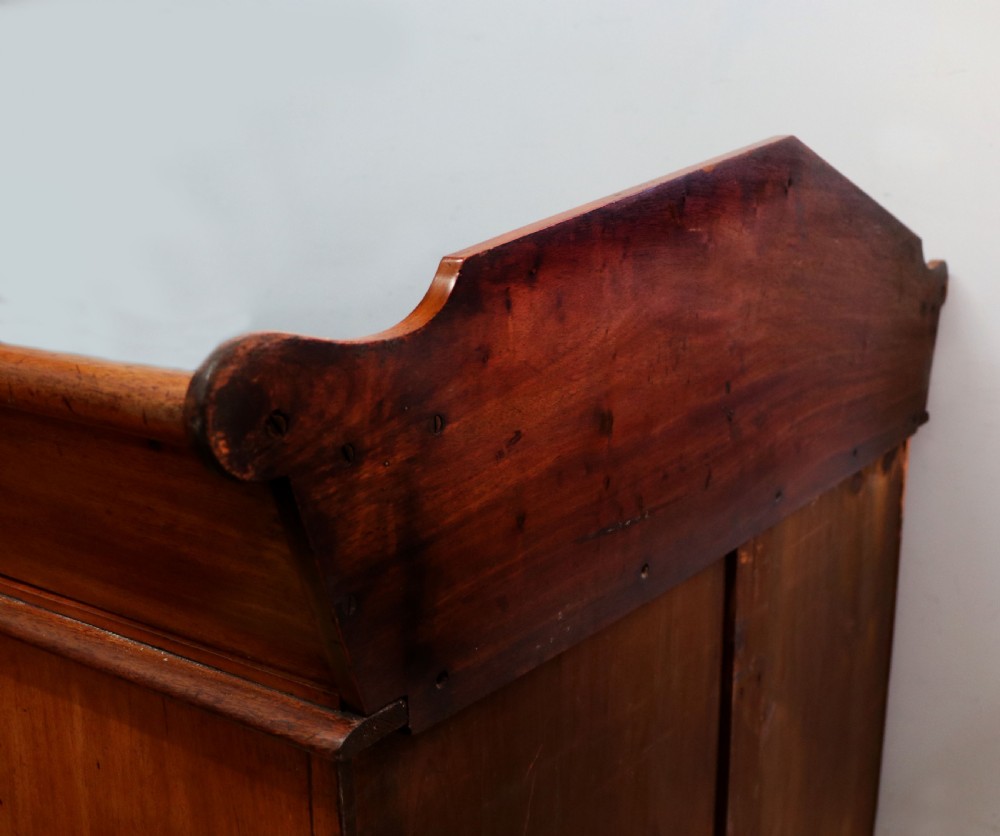 A mid-nineteenth century mahogany chest of drawers featuring two short drawers over two long drawers, turned wooden handles, and a shaped galleried backboard. View XXV