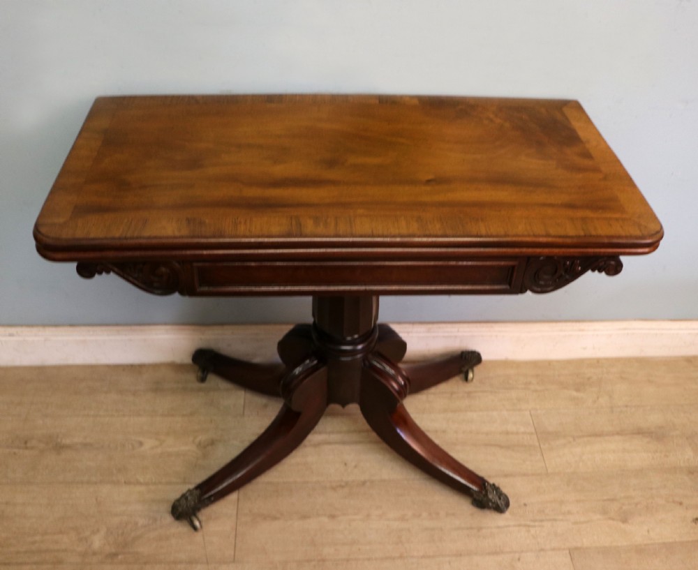 An early 19th-century mahogany tea table featuring a hinged fold-over top, turned central column, and four splayed legs with brass castors. View IV