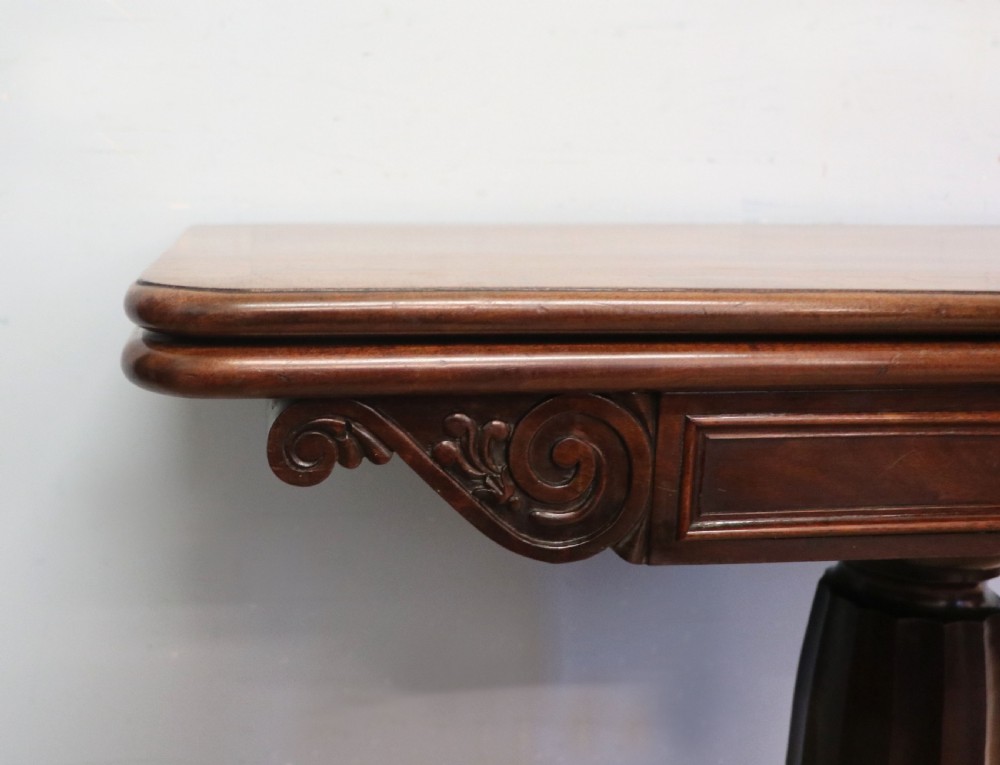 An early 19th-century mahogany tea table featuring a hinged fold-over top, turned central column, and four splayed legs with brass castors. View IX