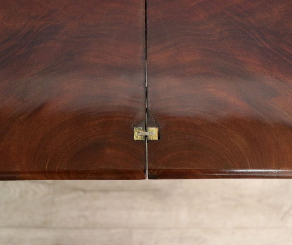 An early 19th-century mahogany tea table featuring a hinged fold-over top, turned central column, and four splayed legs with brass castors. View XIII