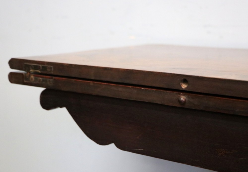 An early 19th-century mahogany tea table featuring a hinged fold-over top, turned central column, and four splayed legs with brass castors. View XVII