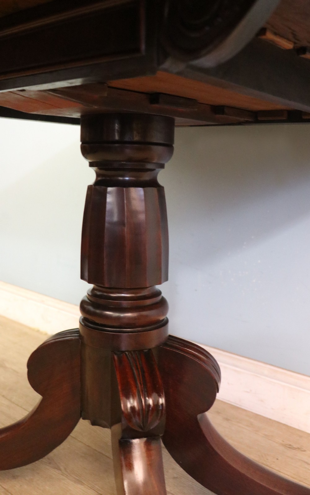 An early 19th-century mahogany tea table featuring a hinged fold-over top, turned central column, and four splayed legs with brass castors. View XXI
