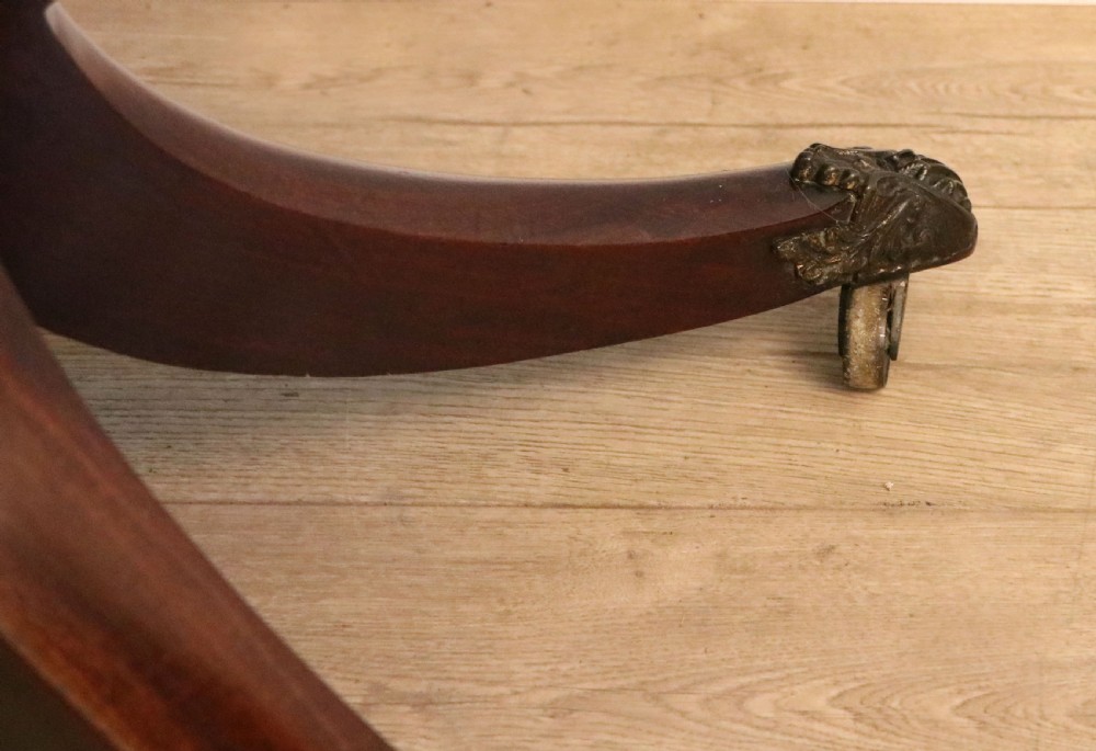 An early 19th-century mahogany tea table featuring a hinged fold-over top, turned central column, and four splayed legs with brass castors. View XXIII