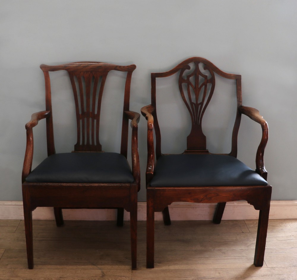 A pair of early 19th century dark timber carver chairs featuring open pierced splats, swept armrests, and dark upholstered seats.