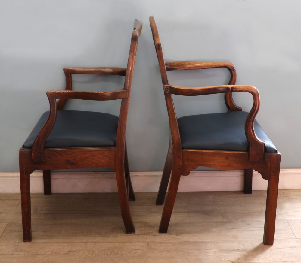 A pair of early 19th century dark timber carver chairs featuring open pierced splats, swept armrests, and dark upholstered seats. View III