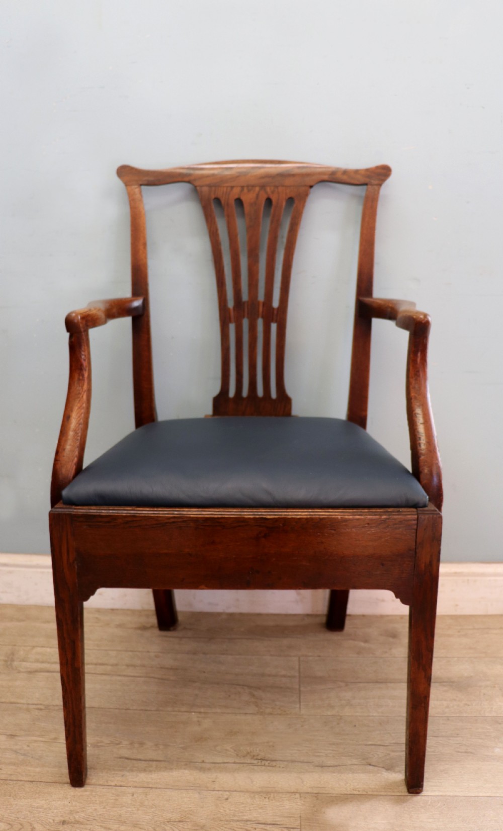 A pair of early 19th century dark timber carver chairs featuring open pierced splats, swept armrests, and dark upholstered seats. View V