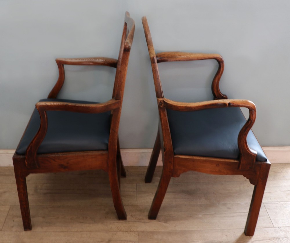 A pair of early 19th century dark timber carver chairs featuring open pierced splats, swept armrests, and dark upholstered seats. View VI