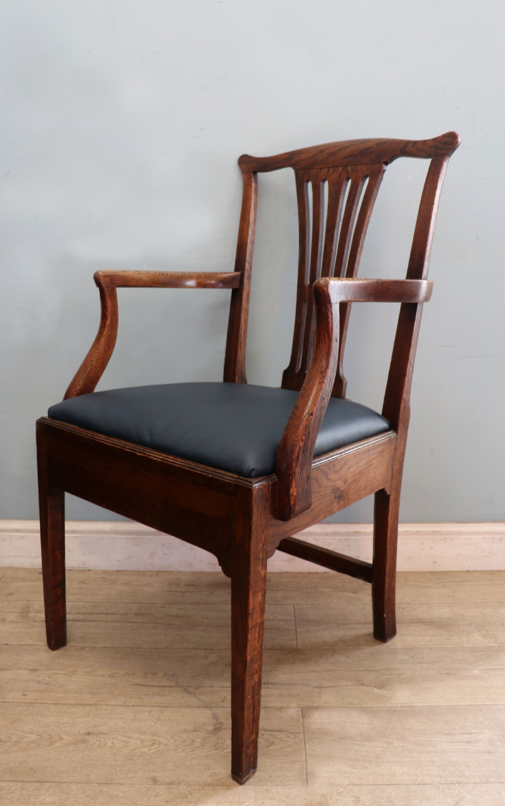 A pair of early 19th century dark timber carver chairs featuring open pierced splats, swept armrests, and dark upholstered seats. View VII