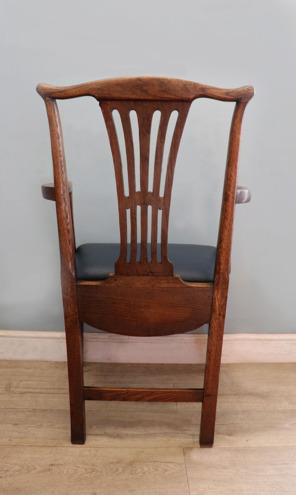 A pair of early 19th century dark timber carver chairs featuring open pierced splats, swept armrests, and dark upholstered seats. View X