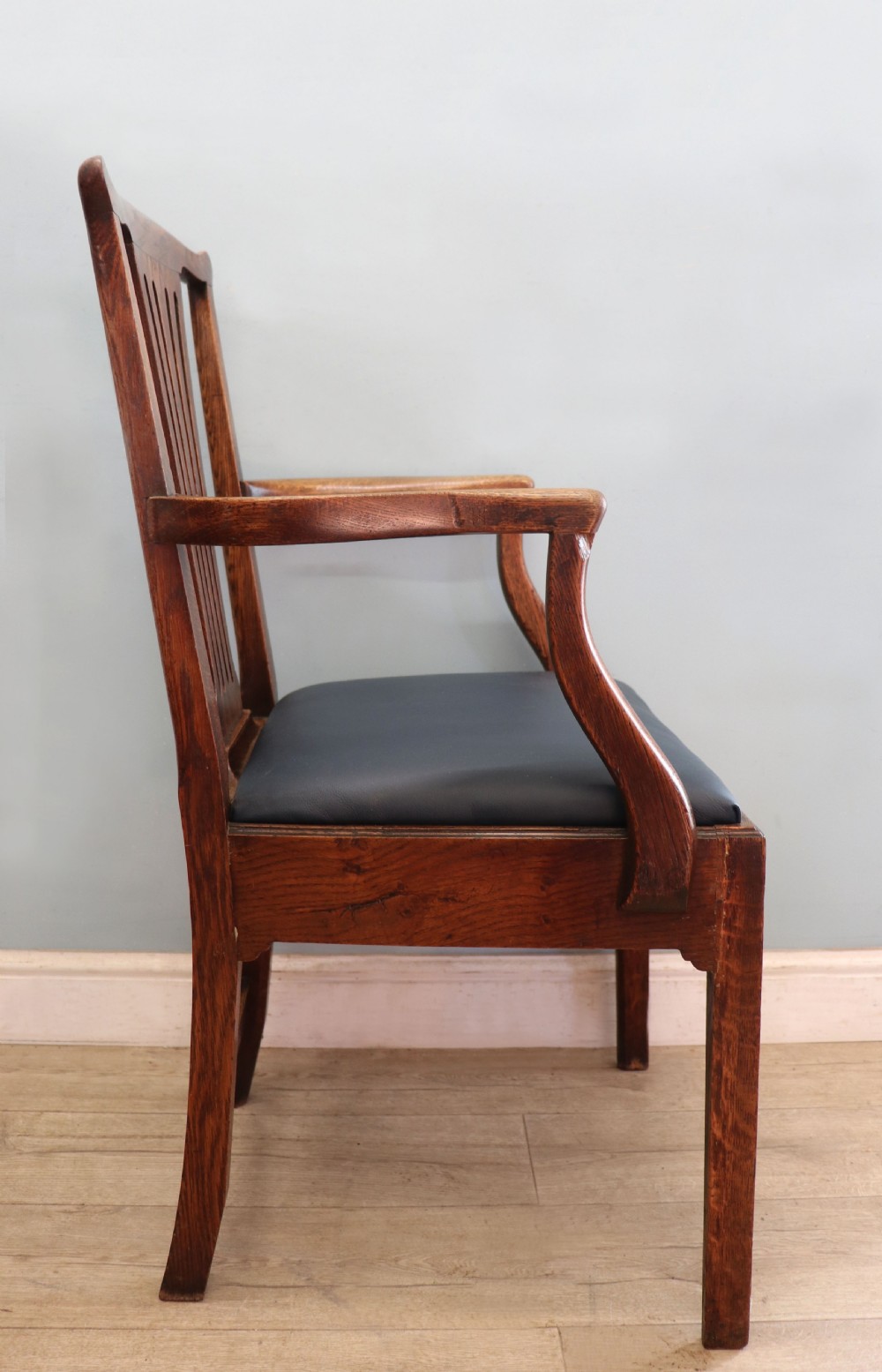 A pair of early 19th century dark timber carver chairs featuring open pierced splats, swept armrests, and dark upholstered seats. View XVIII