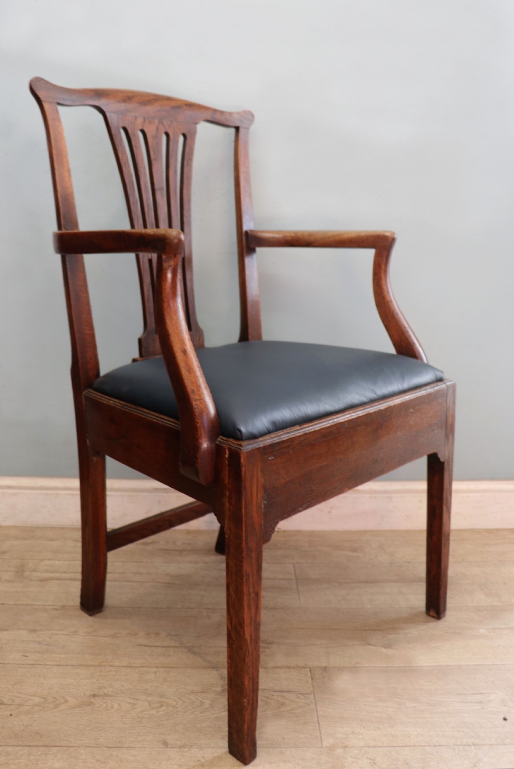 A pair of early 19th century dark timber carver chairs featuring open pierced splats, swept armrests, and dark upholstered seats. View XIX