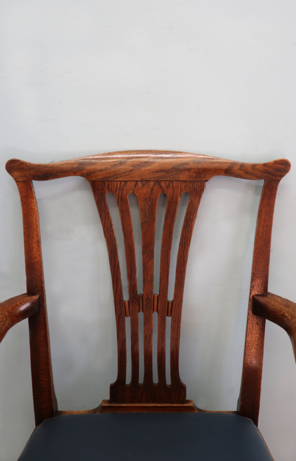 A pair of early 19th century dark timber carver chairs featuring open pierced splats, swept armrests, and dark upholstered seats. View XX