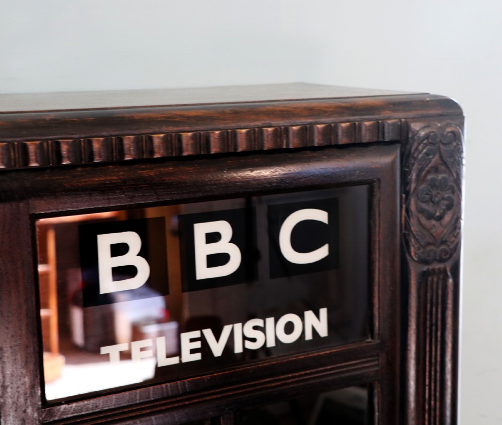 A dark oak glazed cabinet featuring hand-painted white lettering for the British Broadcasting Company across two glass doors. View VII