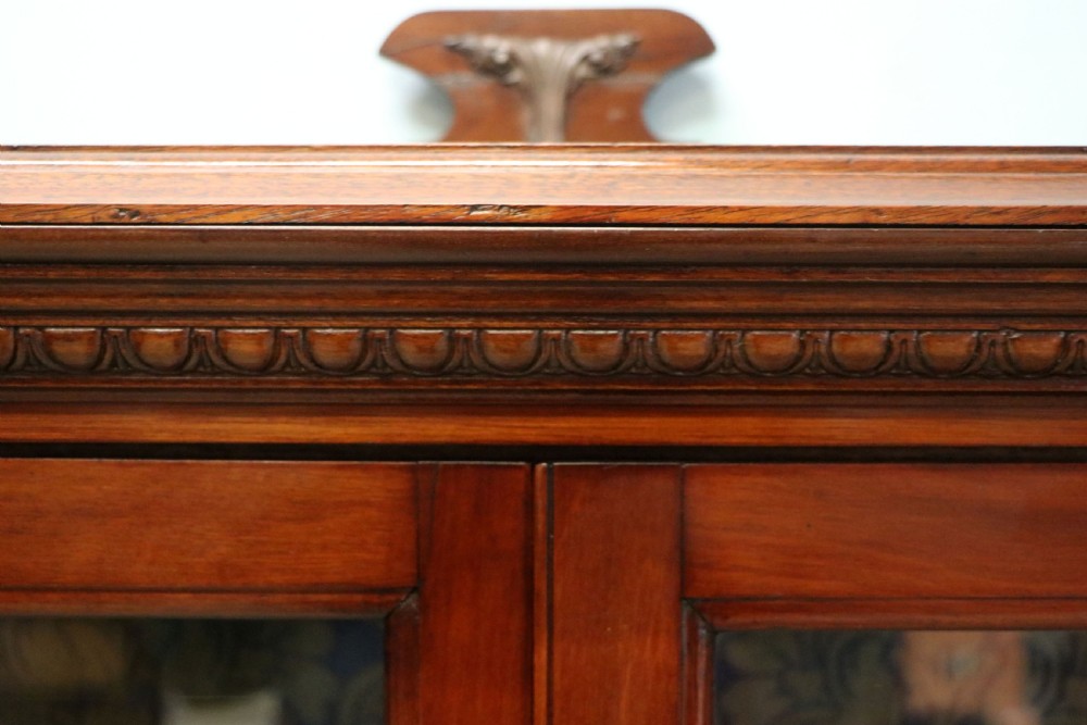 A late nineteenth-century dark mahogany display cabinet featuring two glazed doors adorned with hand-painted gold advertising typography, resting on short cabriole legs. View VIII