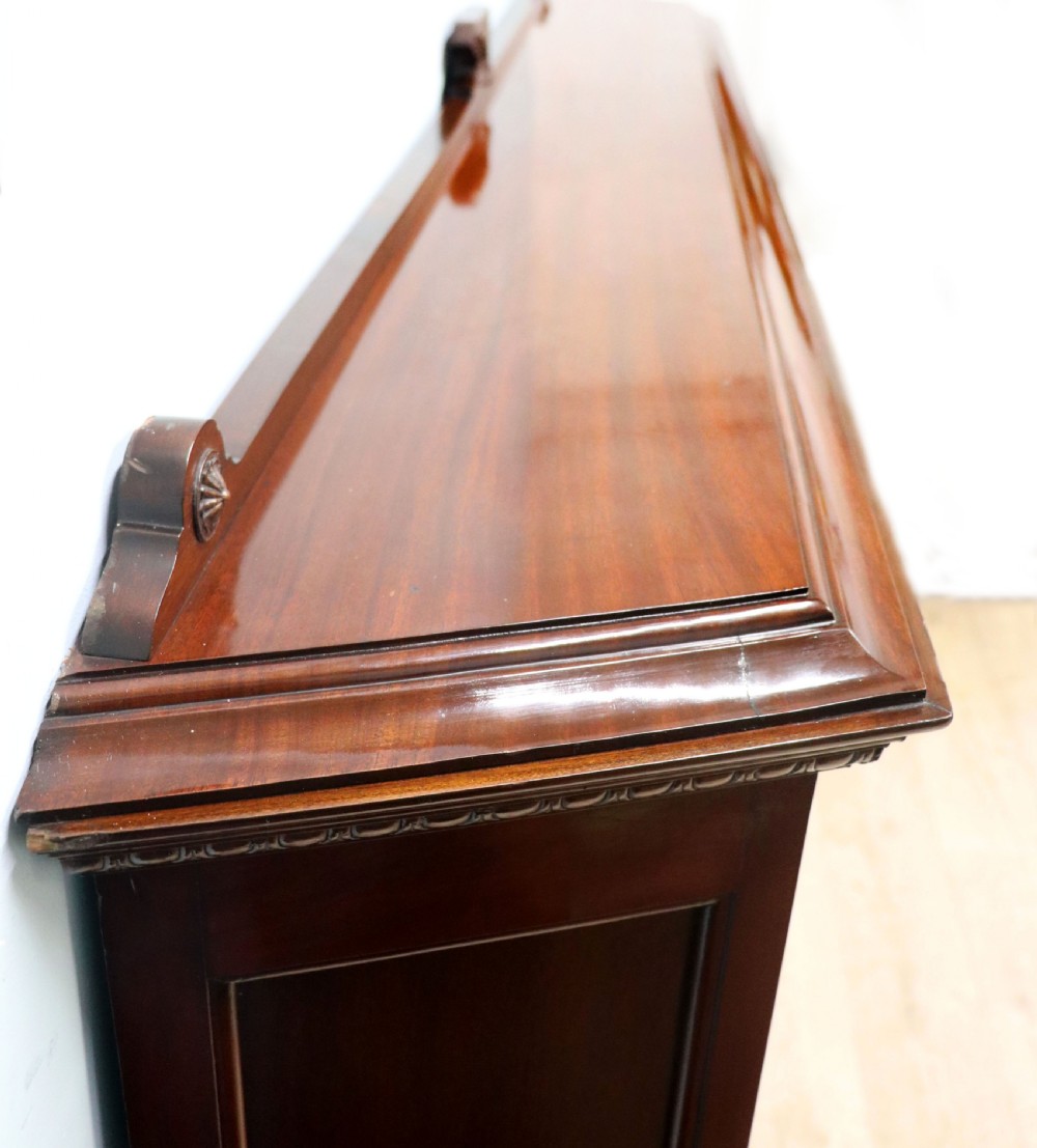 A late nineteenth-century dark mahogany display cabinet featuring two glazed doors adorned with hand-painted gold advertising typography, resting on short cabriole legs. View XI