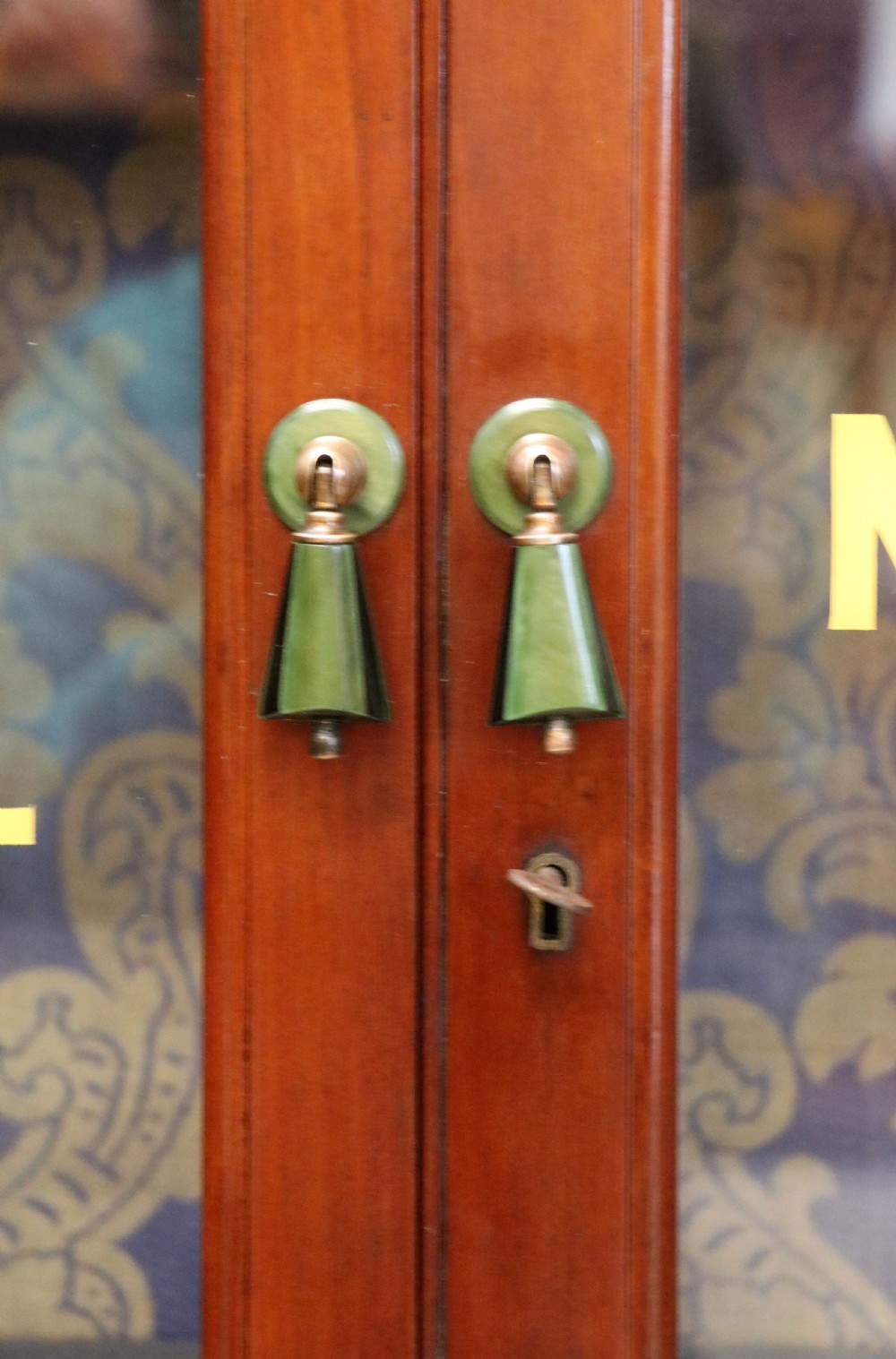 A late nineteenth-century dark mahogany display cabinet featuring two glazed doors adorned with hand-painted gold advertising typography, resting on short cabriole legs. View XVI