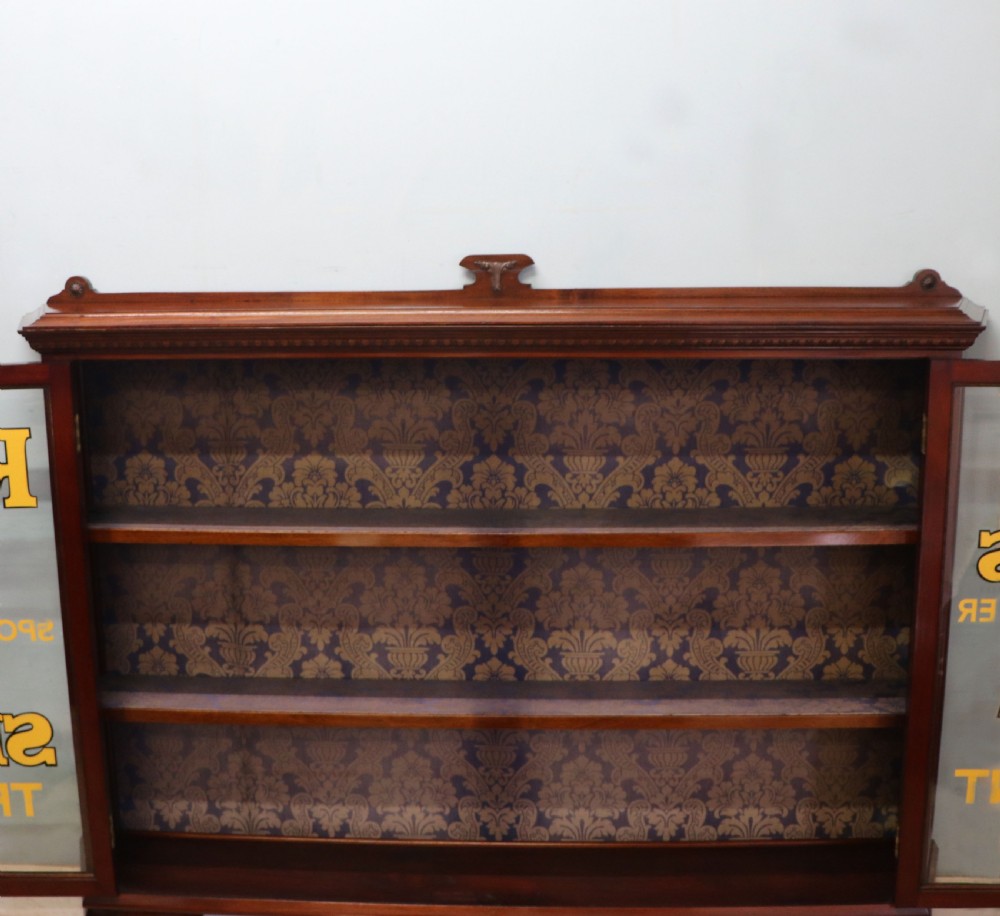 A late nineteenth-century dark mahogany display cabinet featuring two glazed doors adorned with hand-painted gold advertising typography, resting on short cabriole legs. View XVIII