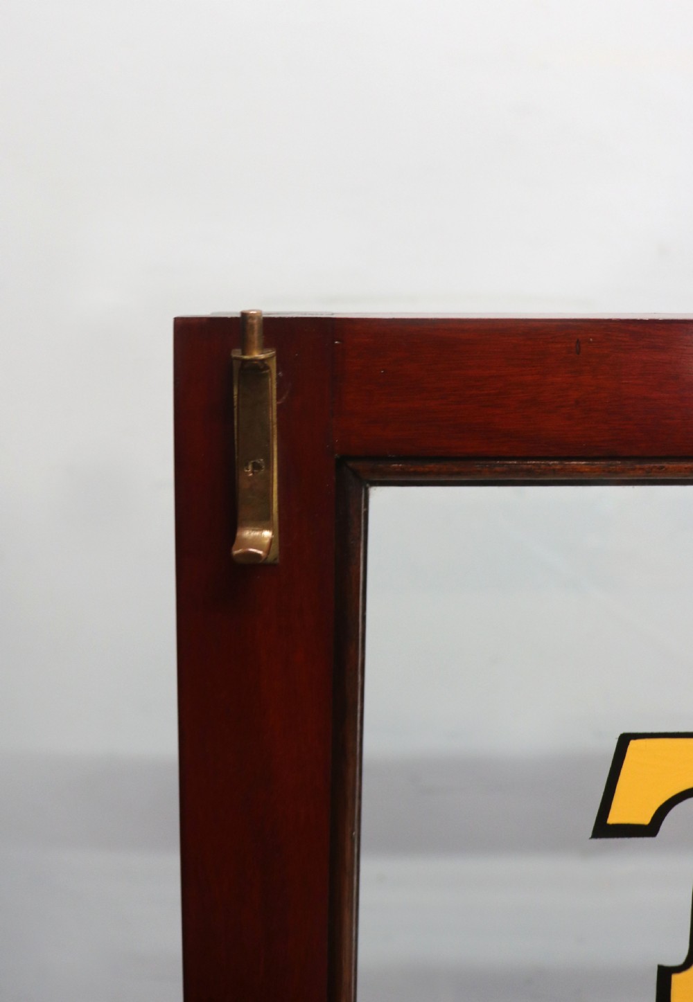 A late nineteenth-century dark mahogany display cabinet featuring two glazed doors adorned with hand-painted gold advertising typography, resting on short cabriole legs. View XXIII