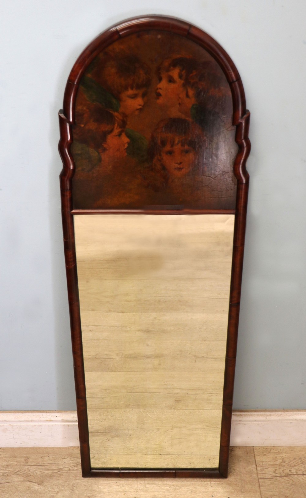 A tall, arched 19th-century mahogany wall mirror featuring an upper oil painting of childrens faces above a rectangular mirror glass. View II