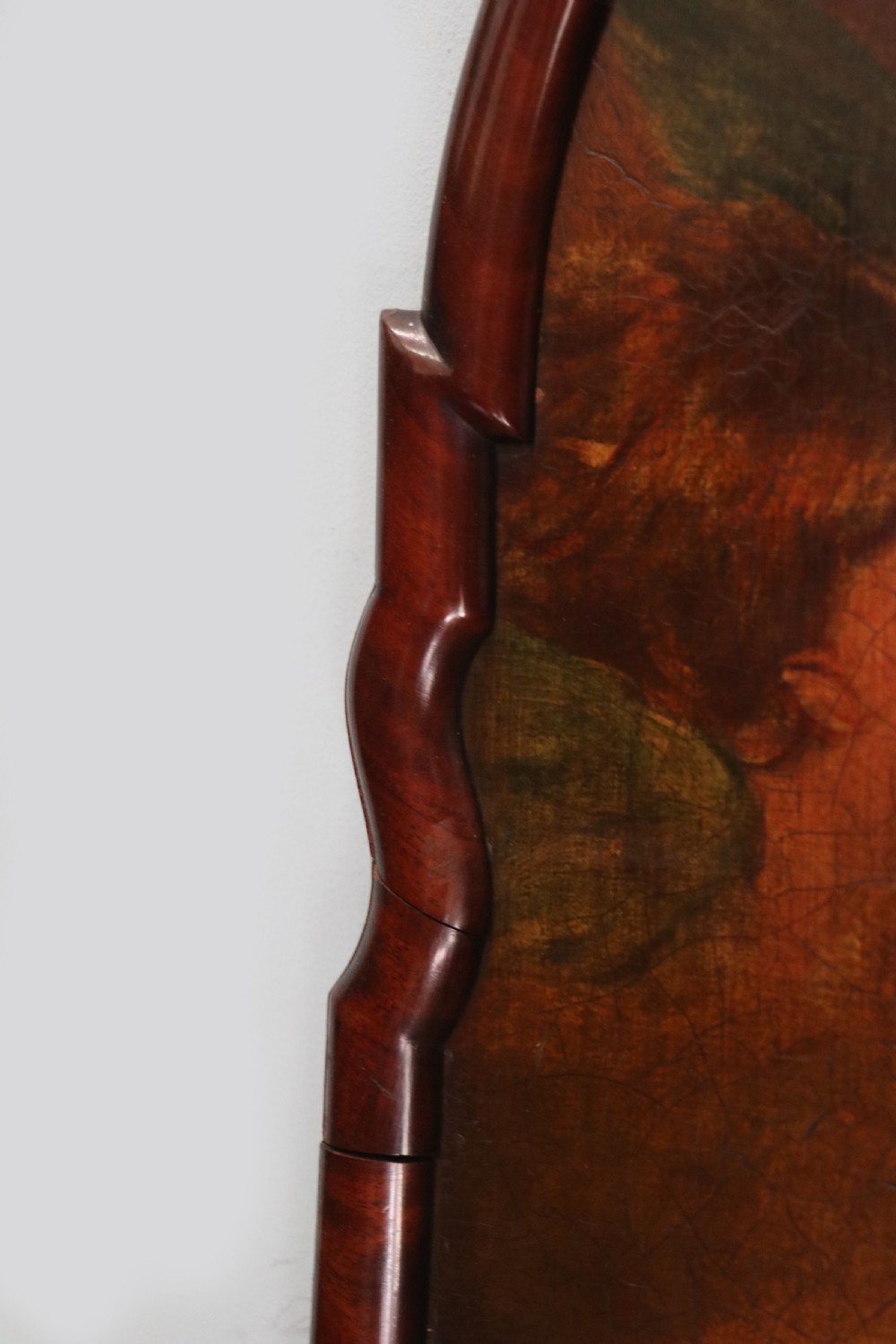 A tall, arched 19th-century mahogany wall mirror featuring an upper oil painting of childrens faces above a rectangular mirror glass. View IV