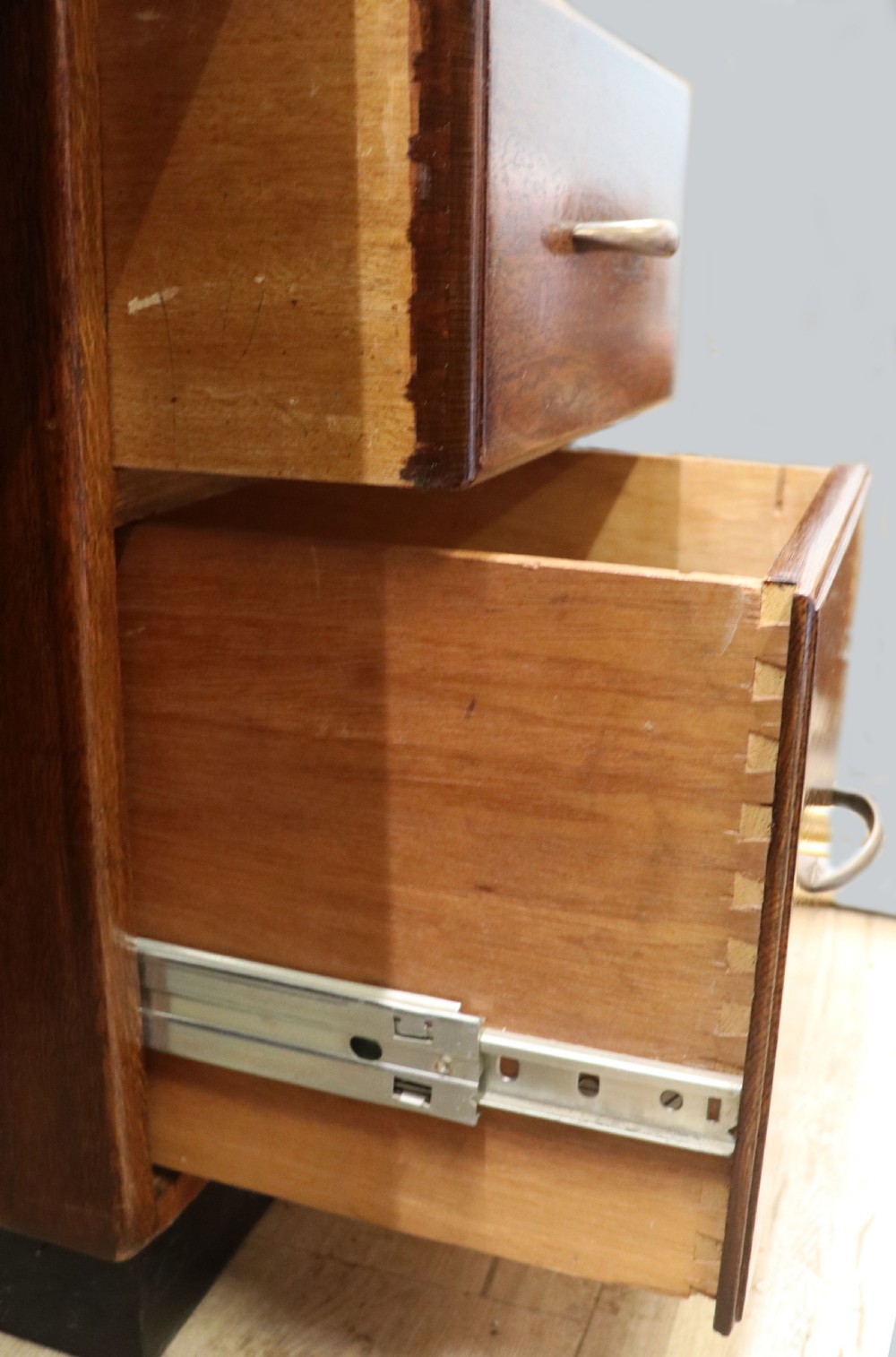 A twin-pedestal mid-century oak office desk featuring seven drawers with brass pull handles and a dark plinth base. View XV