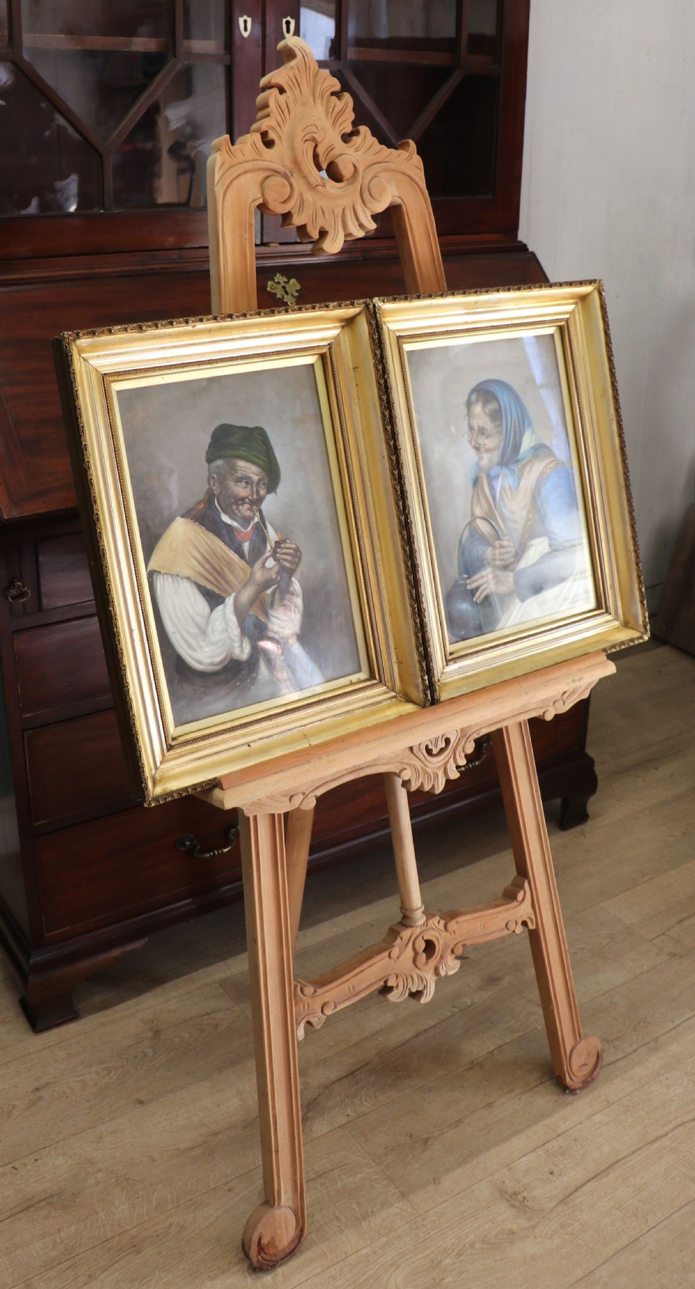 A pair of framed Italian oil portraits depicting an elderly man smoking a pipe and an elderly woman wearing a blue headscarf, both set in matching giltwood frames. View II