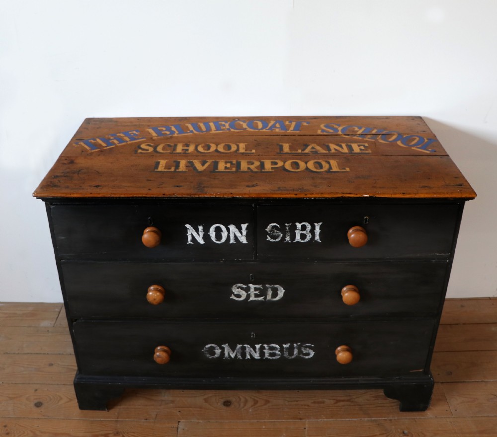 A Victorian black painted pine chest of drawers featuring a natural timber top with hand-painted lettering and turned wooden knobs.