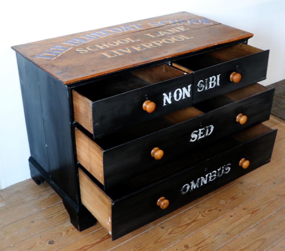 A Victorian black painted pine chest of drawers featuring a natural timber top with hand-painted lettering and turned wooden knobs. View VI