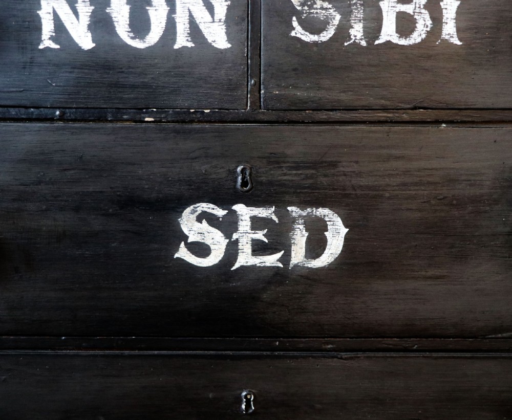 A Victorian black painted pine chest of drawers featuring a natural timber top with hand-painted lettering and turned wooden knobs. View XI