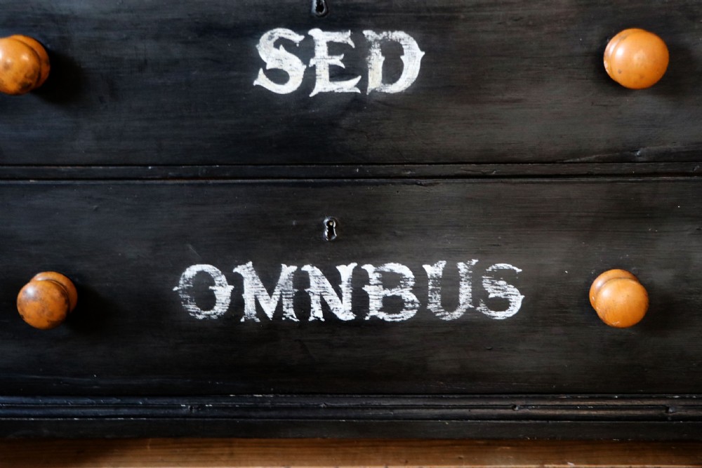 A Victorian black painted pine chest of drawers featuring a natural timber top with hand-painted lettering and turned wooden knobs. View XII