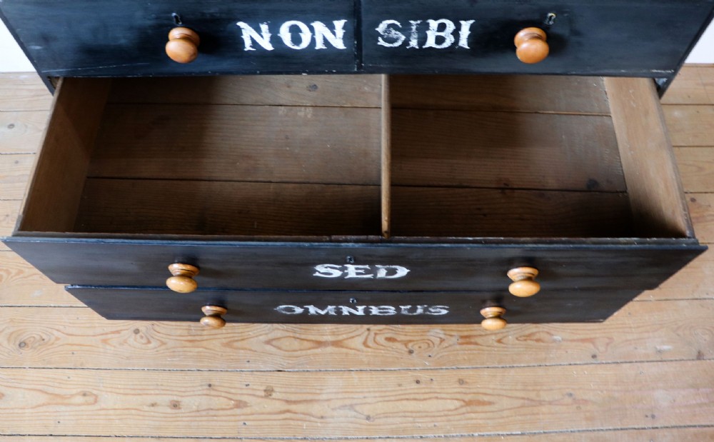 A Victorian black painted pine chest of drawers featuring a natural timber top with hand-painted lettering and turned wooden knobs. View XVIII