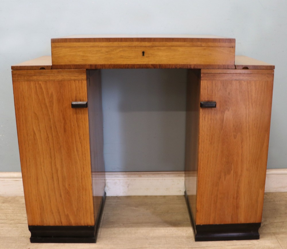 An Art Deco walnut pedestal desk featuring a glass-topped centre writing surface and hinged fold-out side flaps supported by twin cabinet bases. View III
