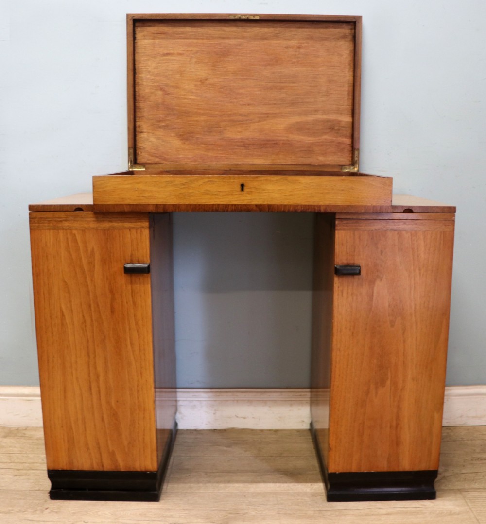 An Art Deco walnut pedestal desk featuring a glass-topped centre writing surface and hinged fold-out side flaps supported by twin cabinet bases. View V