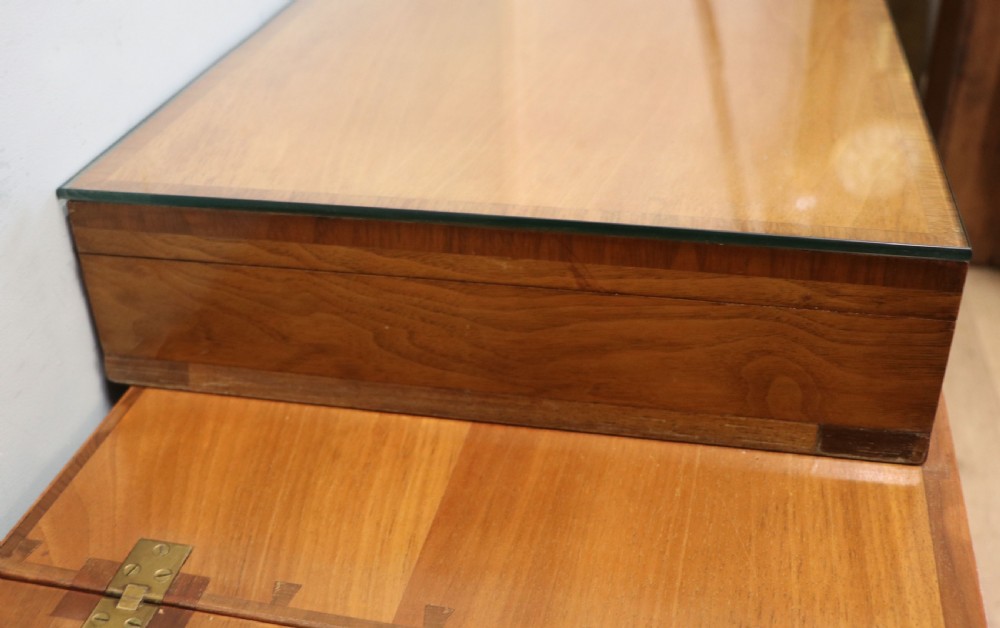 An Art Deco walnut pedestal desk featuring a glass-topped centre writing surface and hinged fold-out side flaps supported by twin cabinet bases. View XVI