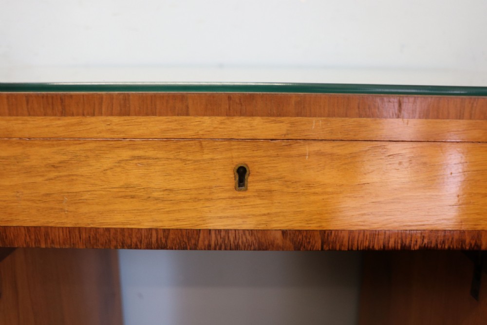 An Art Deco walnut pedestal desk featuring a glass-topped centre writing surface and hinged fold-out side flaps supported by twin cabinet bases. View XVII