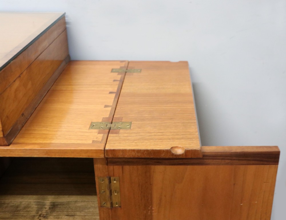 An Art Deco walnut pedestal desk featuring a glass-topped centre writing surface and hinged fold-out side flaps supported by twin cabinet bases. View XIX