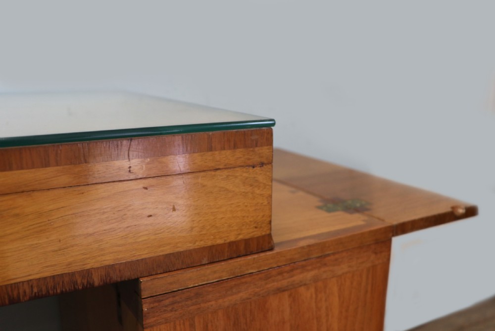 An Art Deco walnut pedestal desk featuring a glass-topped centre writing surface and hinged fold-out side flaps supported by twin cabinet bases. View XXI