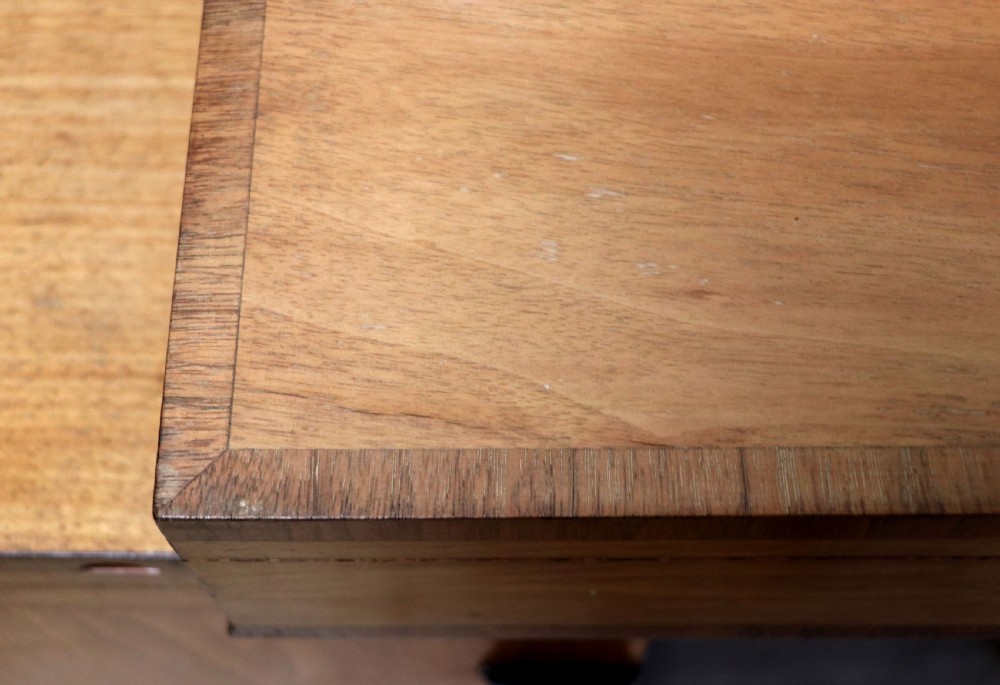 An Art Deco walnut pedestal desk featuring a glass-topped centre writing surface and hinged fold-out side flaps supported by twin cabinet bases. View XXIII